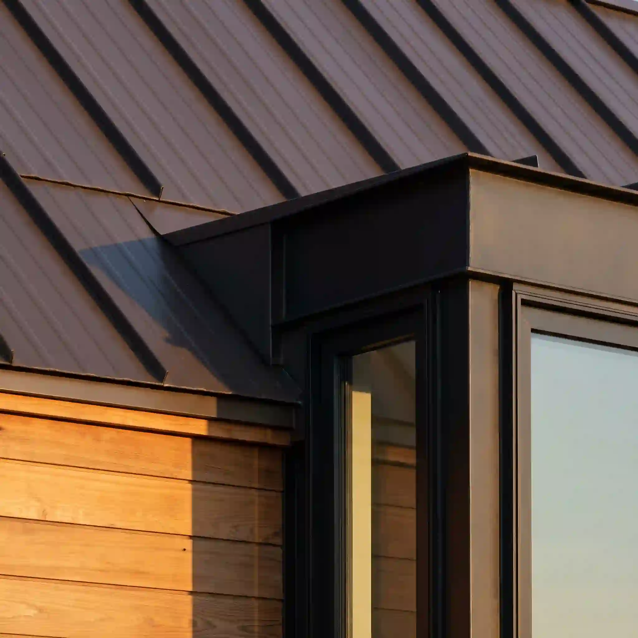 Bronze standing seam roof meets cedar siding on a custom Burcham home